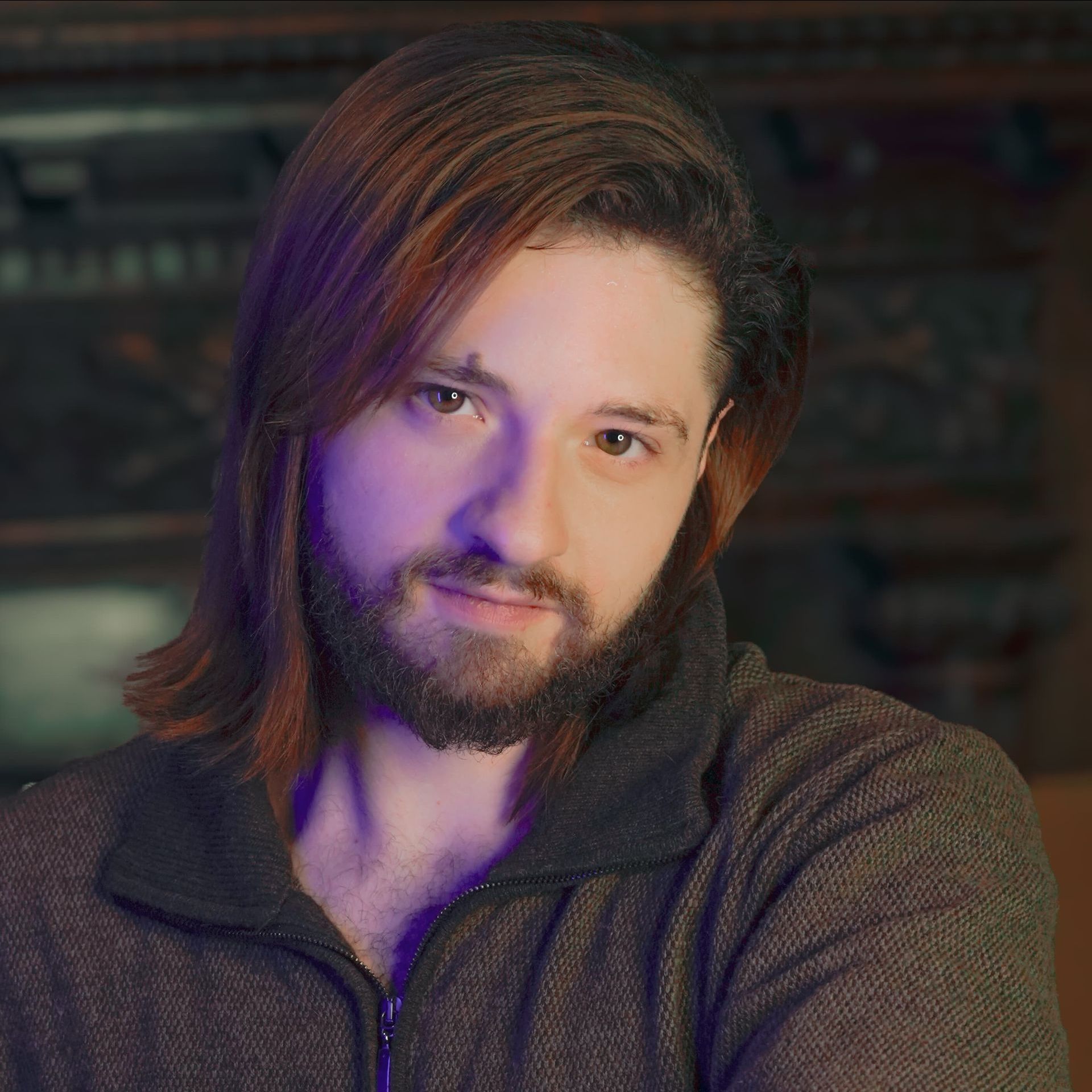 A man with long hair and a beard is looking at the camera.