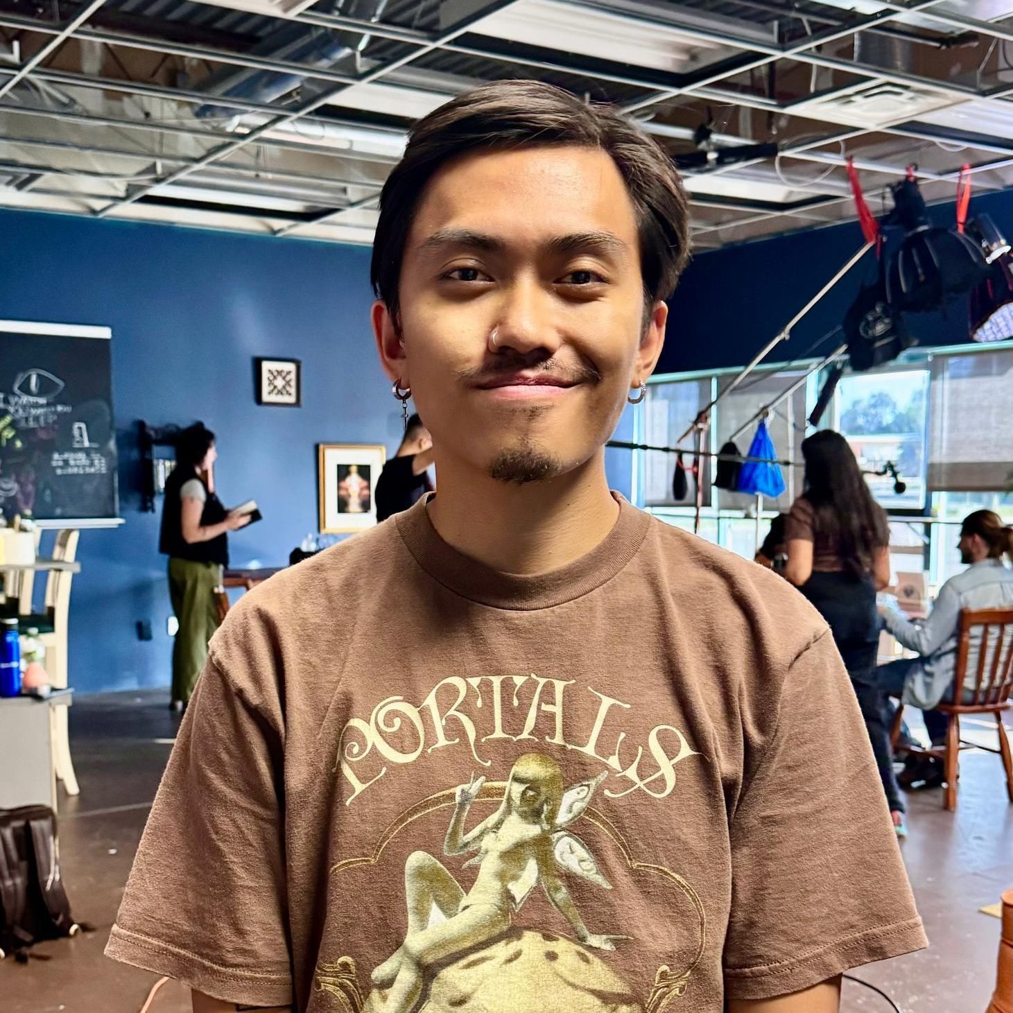 A man wearing a portals t-shirt is standing in a room.