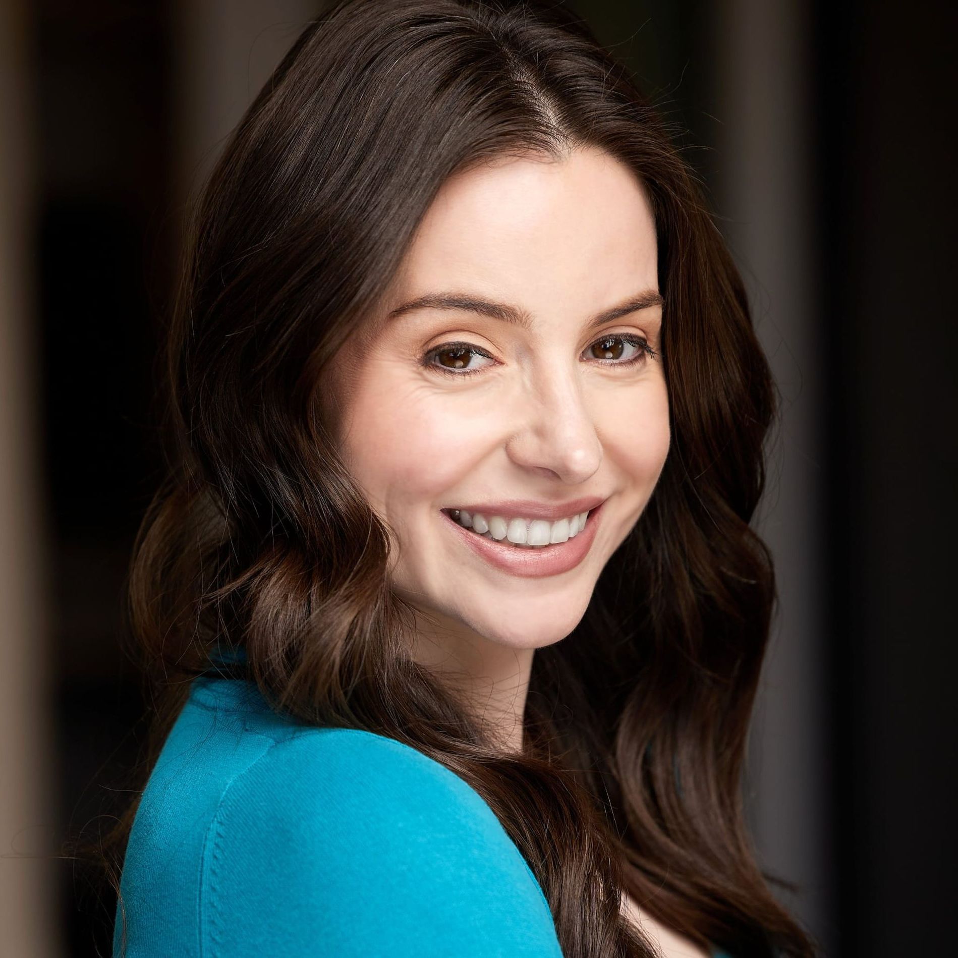 The woman is wearing a blue shirt and smiling for the camera.