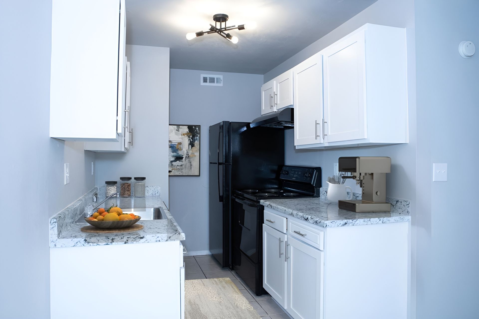 a kitchen with white cabinets and a black refrigerator