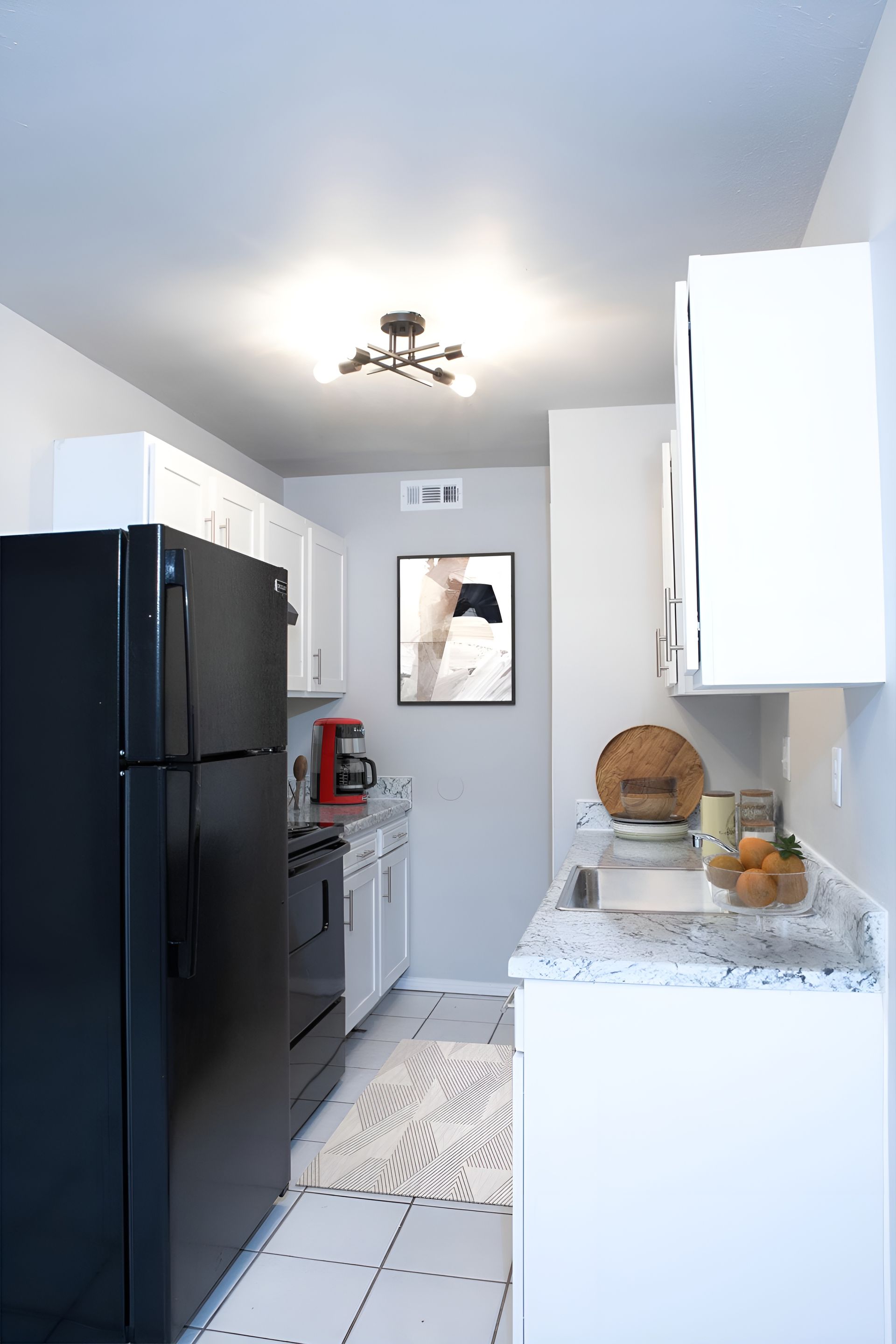 a kitchen with a black refrigerator and white cabinets