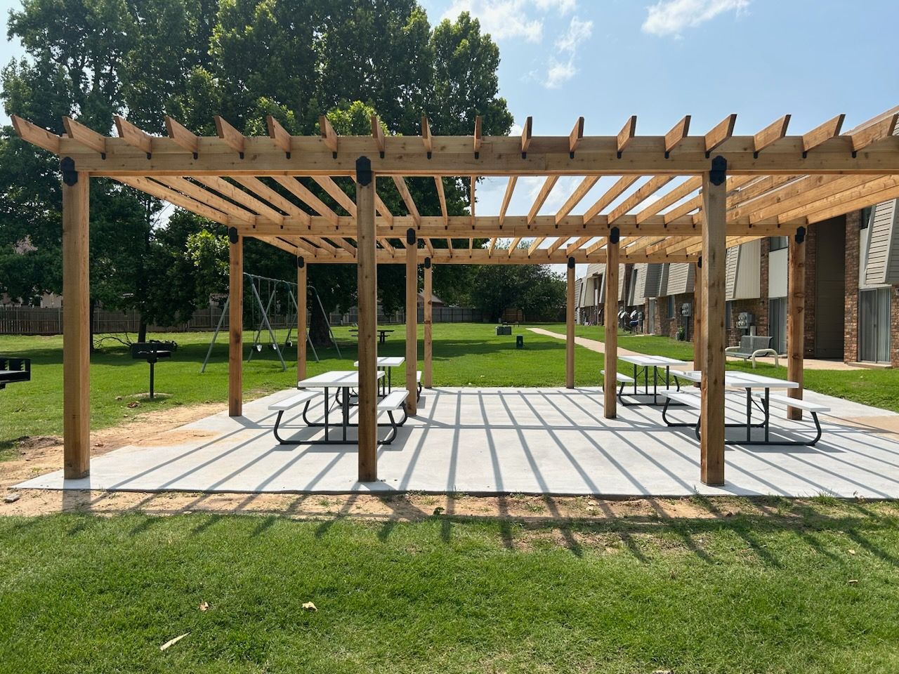a wooden pergola with picnic tables underneath it