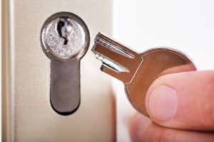 A person is holding a broken key in front of a door lock.