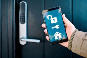 A person is holding a smart phone in front of a door lock.