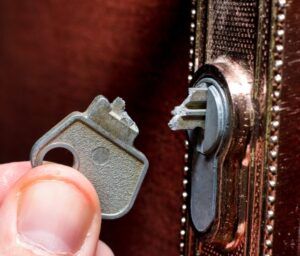 A person is holding a key in front of a door lock.