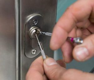 A person is using a screwdriver to open a door lock.