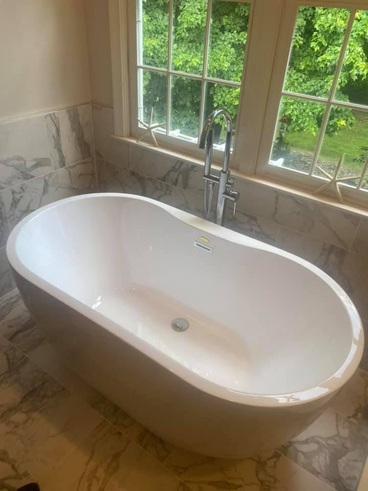 A white bathtub is sitting in a bathroom next to a window.