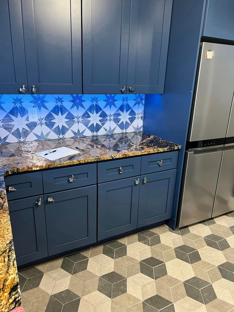A kitchen with blue cabinets and a stainless steel refrigerator.