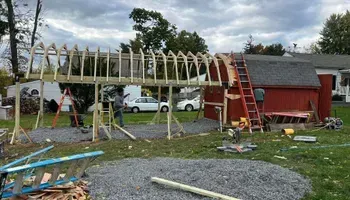 A wooden structure is being built in the backyard of a house.