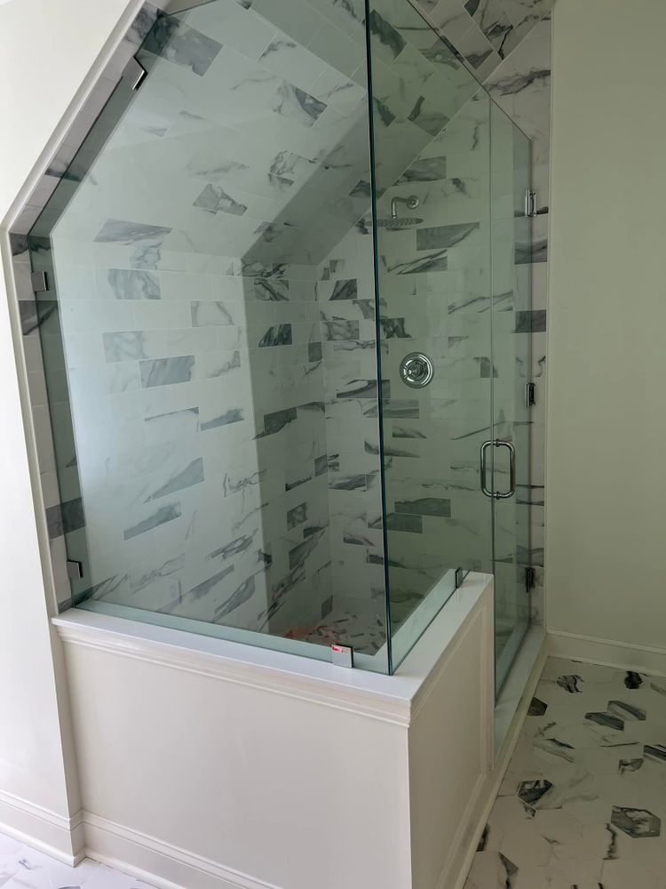 A bathroom with a walk in shower with a glass door.