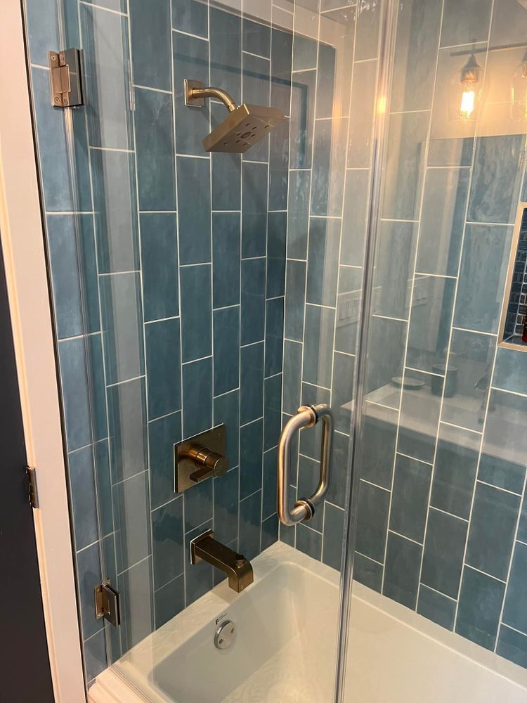 A bathroom with blue tiles and a bathtub and shower.