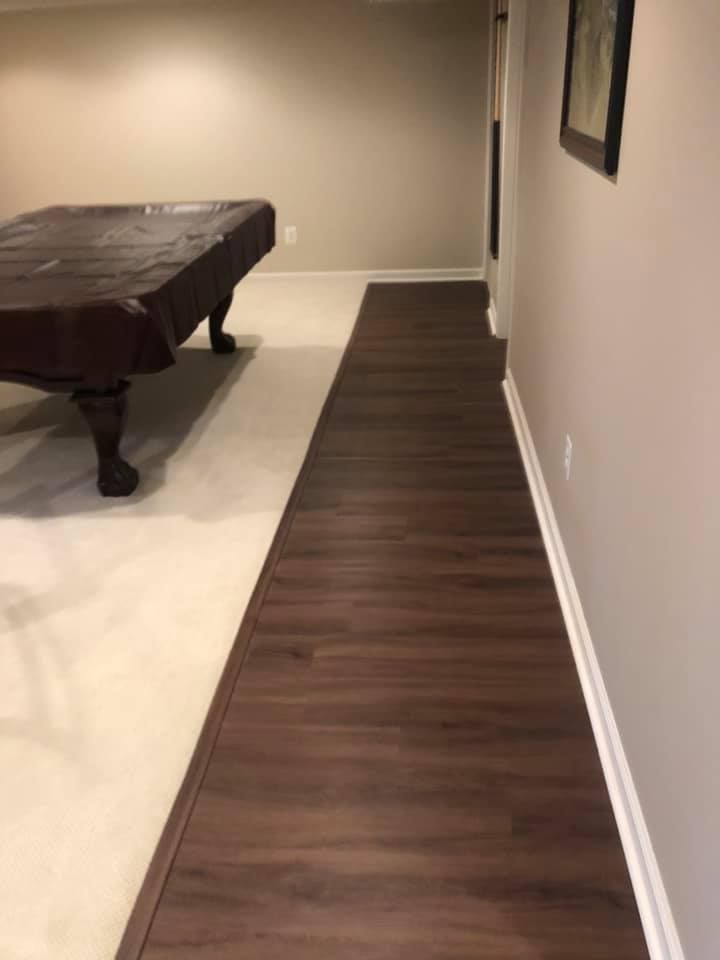 A pool table is sitting in a hallway next to a wooden floor.