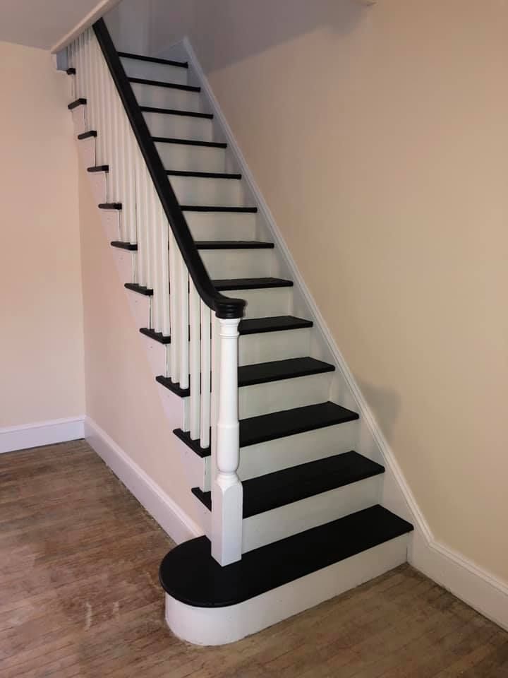 A white staircase with black steps and a white railing
