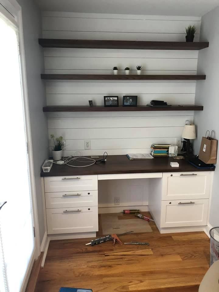 A room with a desk , shelves and a window.