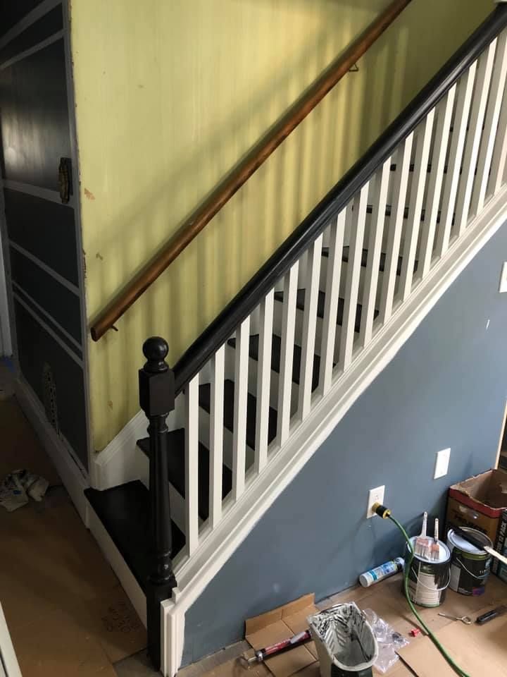 A staircase with a black railing is being painted.