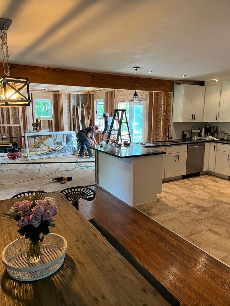 A kitchen under construction with a table and a vase of flowers on it.