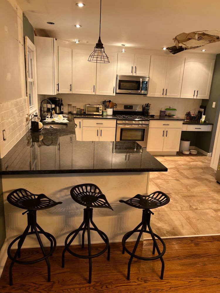 A kitchen with white cabinets and black counter tops