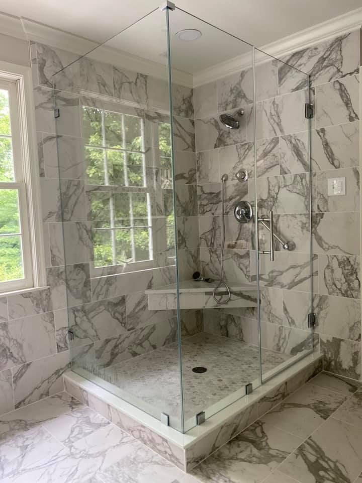 A bathroom with marble tiles and a walk in shower with a glass door.