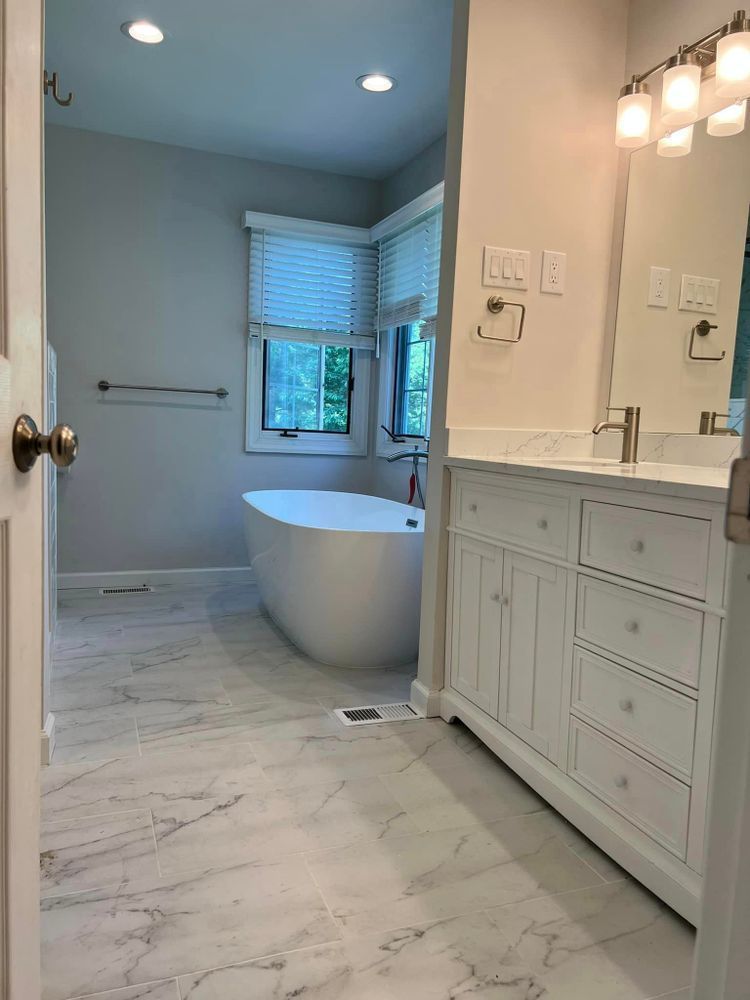 A bathroom with a tub , sink , mirror and window.