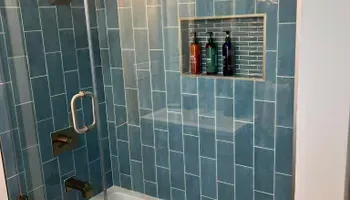 A bathroom with blue tiles and a glass shower door.