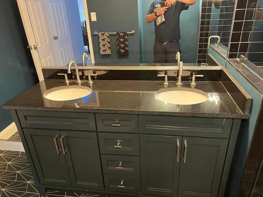 A man is taking a picture of himself in a bathroom with two sinks.