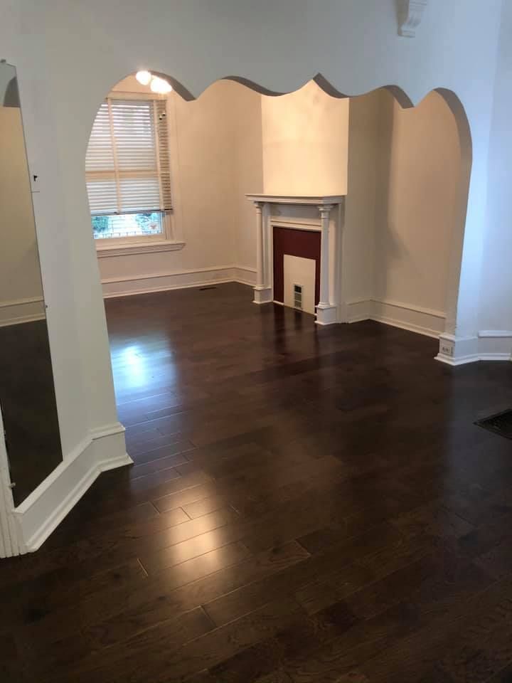 An empty living room with hardwood floors and a fireplace.