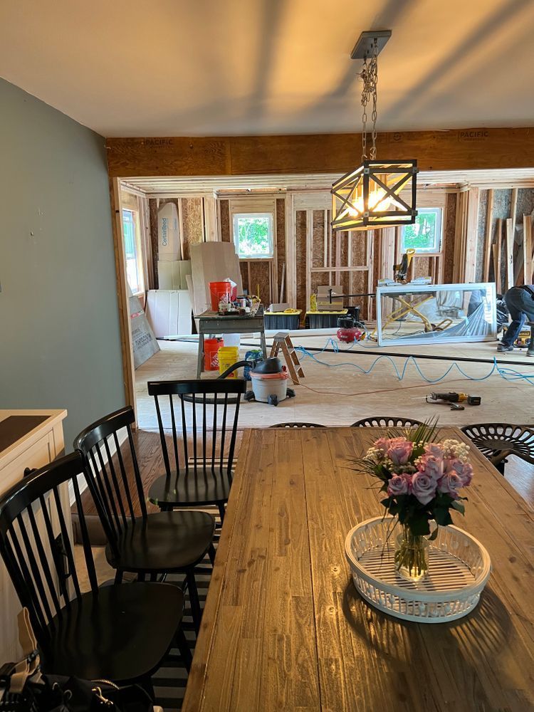 A dining room table with chairs and a vase of flowers on it.