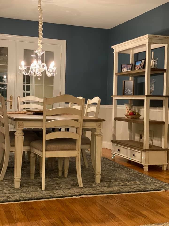 A dining room with a table and chairs and a bookshelf.