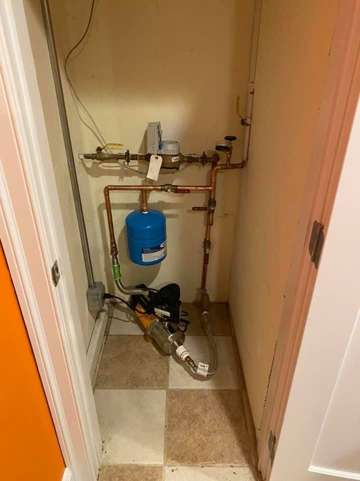 A closet with a water tank and pipes in it.