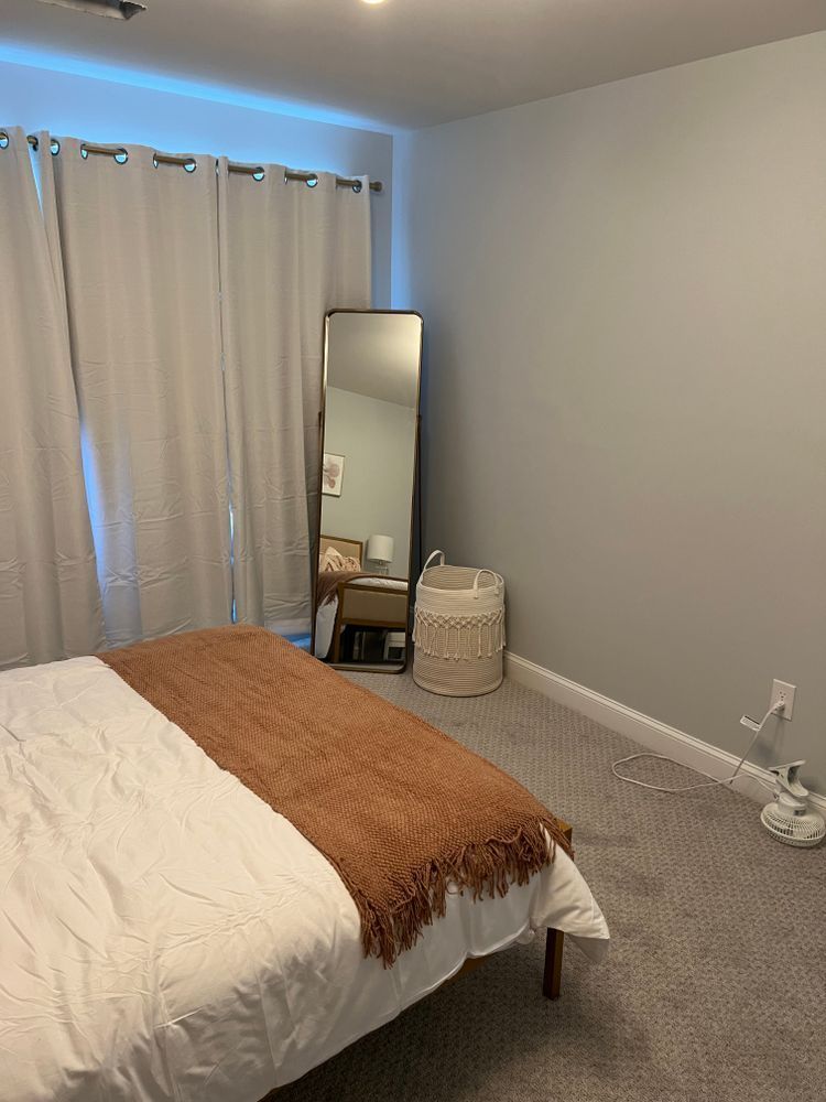 A bedroom with a bed , mirror and window.