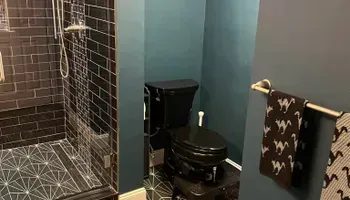 A bathroom with a toilet , shower , and towel rack.