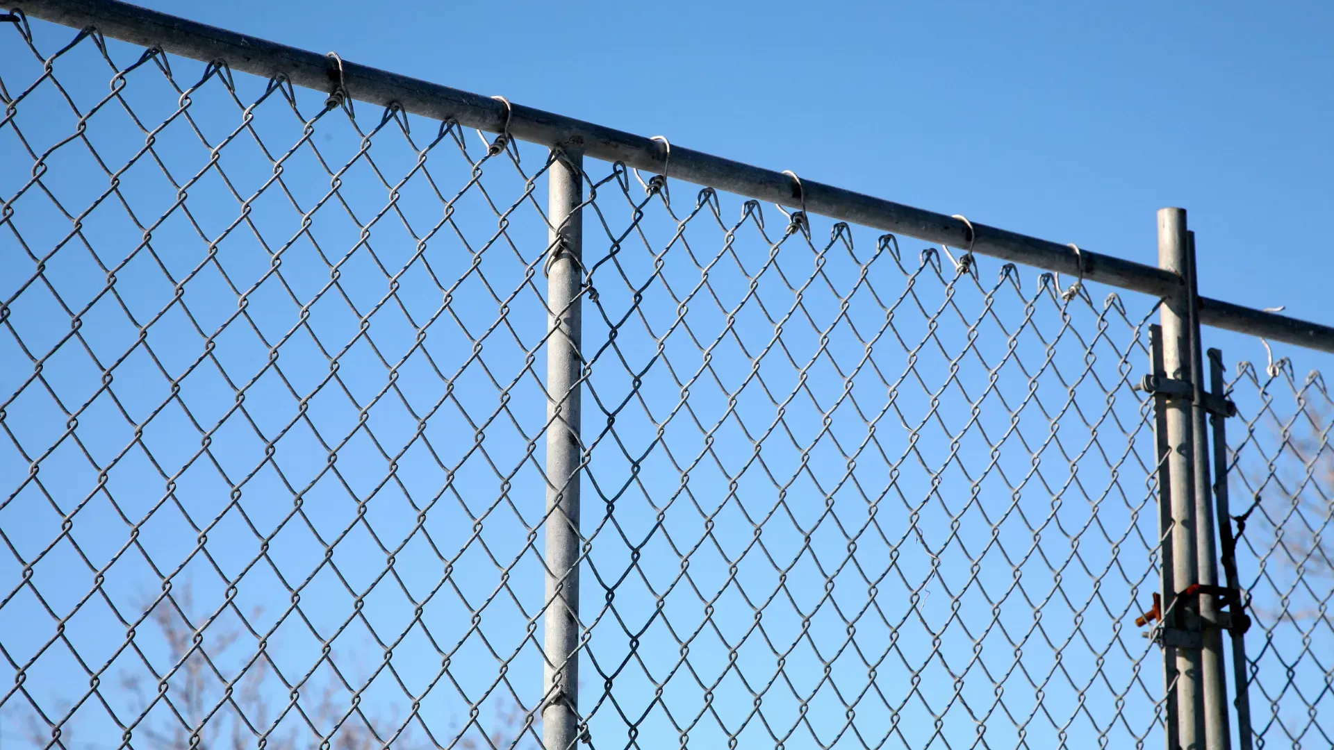 Chain-link fence with blue sky background.