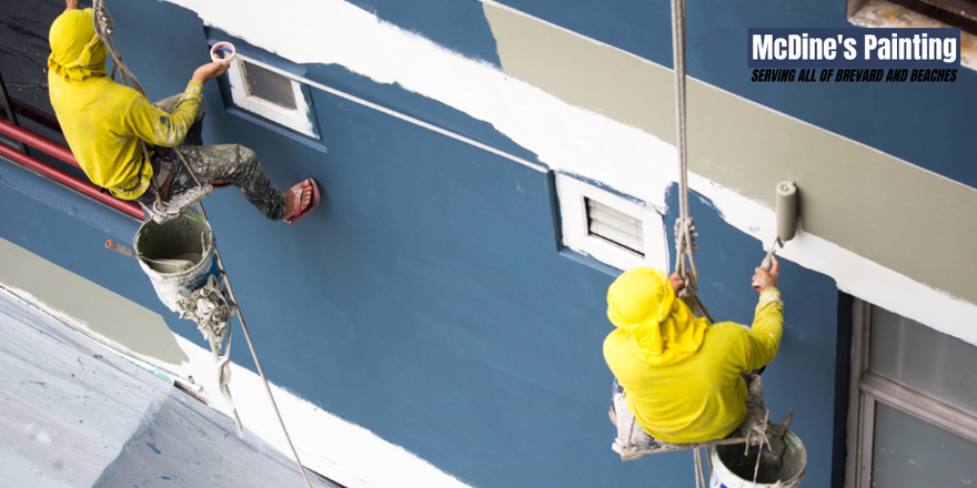 Two men are painting a building with mcdine 's painting written on the bottom