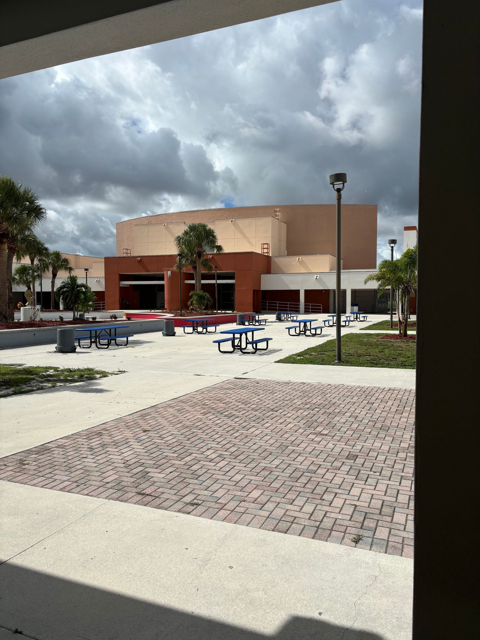 A building with a lot of blue picnic tables in front of it