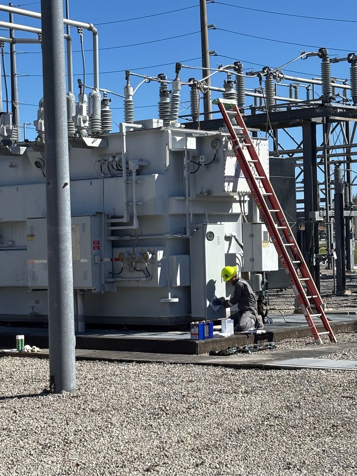 A man is working on a transformer with a red ladder