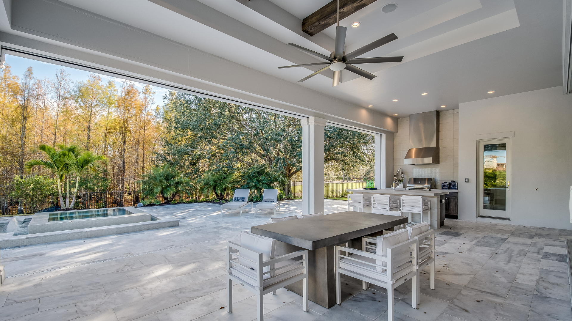 A patio with a table and chairs and a ceiling fan.