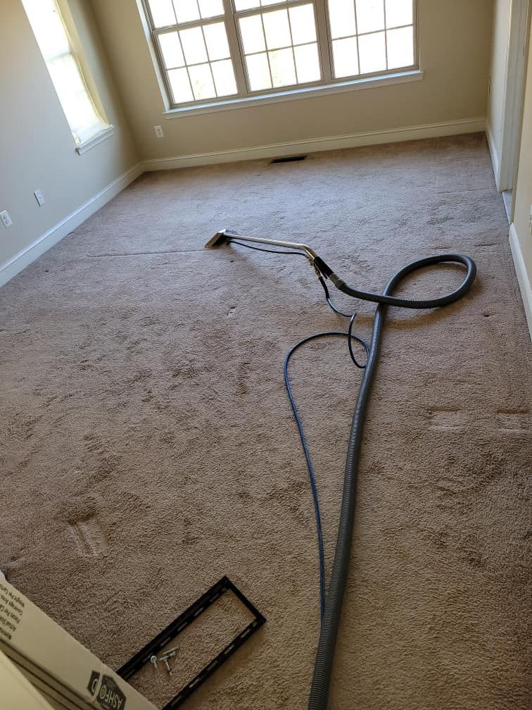 Carpet being cleaned in a room with a window. The carpet is light brown, and a cleaning tool is in the center.