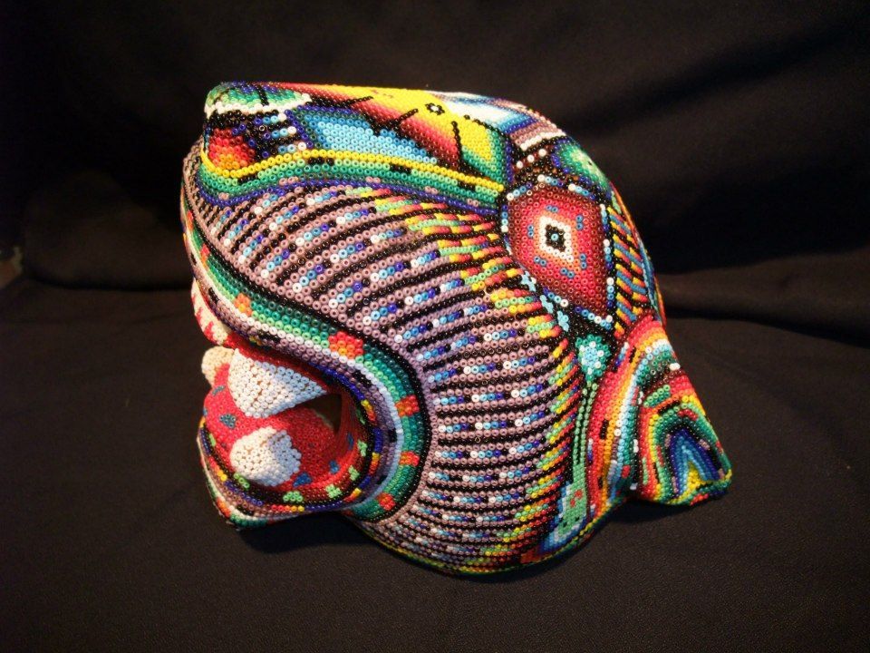 A dining room with a glass table, white chairs, a modern chandelier, and three framed abstract art pieces on the wall.