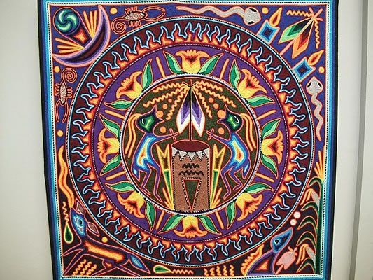 Square sand art with a central red circle, four dragonfly motifs, and colorful floral patterns on a dark blue background.