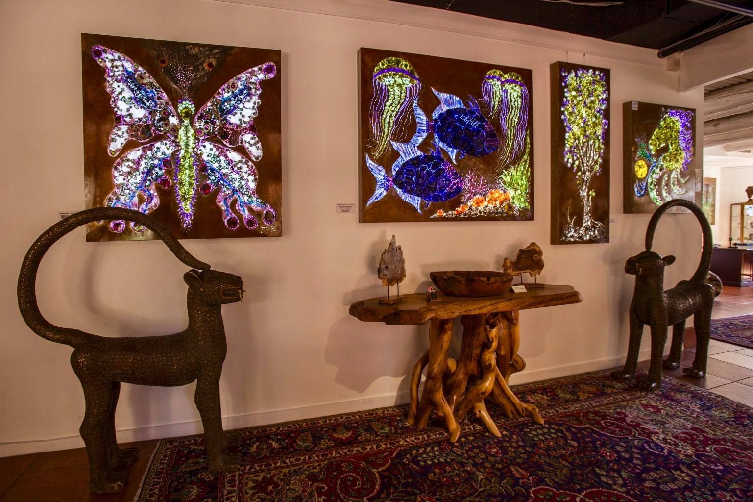 A hand-painted ceramic vase with spiral designs sits on a rustic wooden stand in a shop window overlooking a street.
