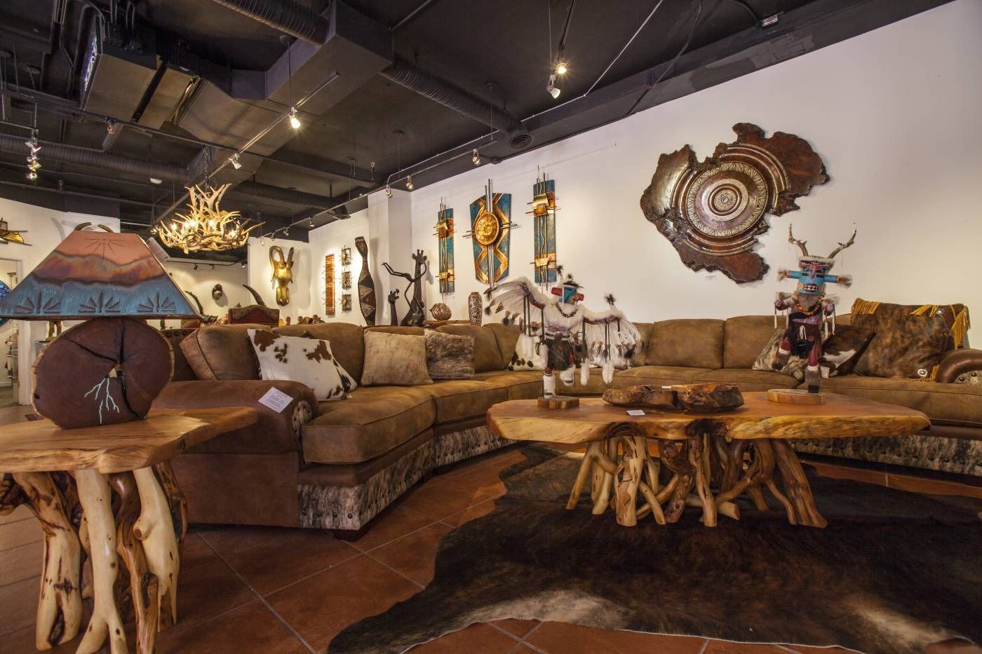 Rustic furniture store interior featuring leather sofas, natural wood tables, and desert-inspired wall art.
