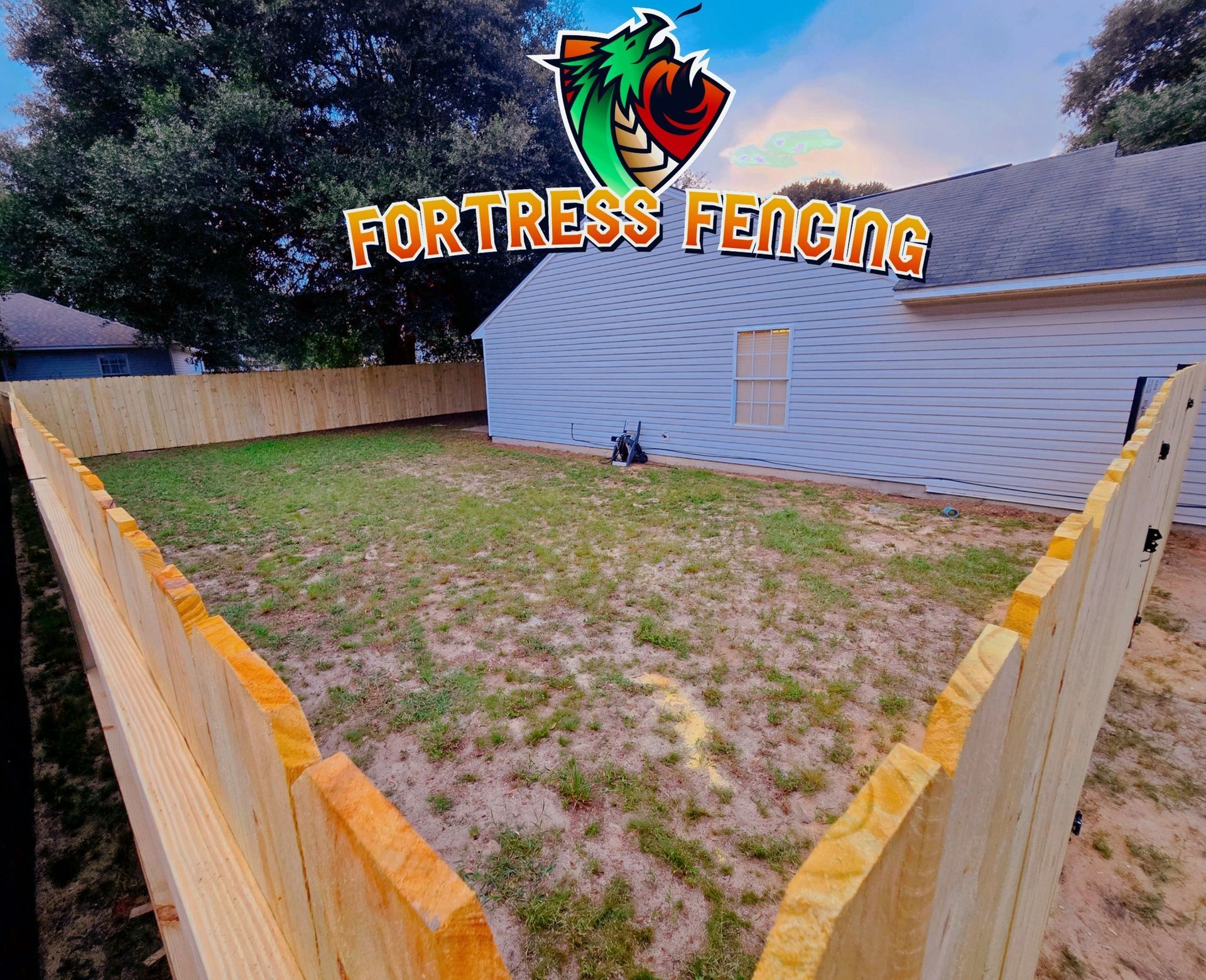 A new wooden fence encloses a backyard, showcasing the work of Fortress Fencing.