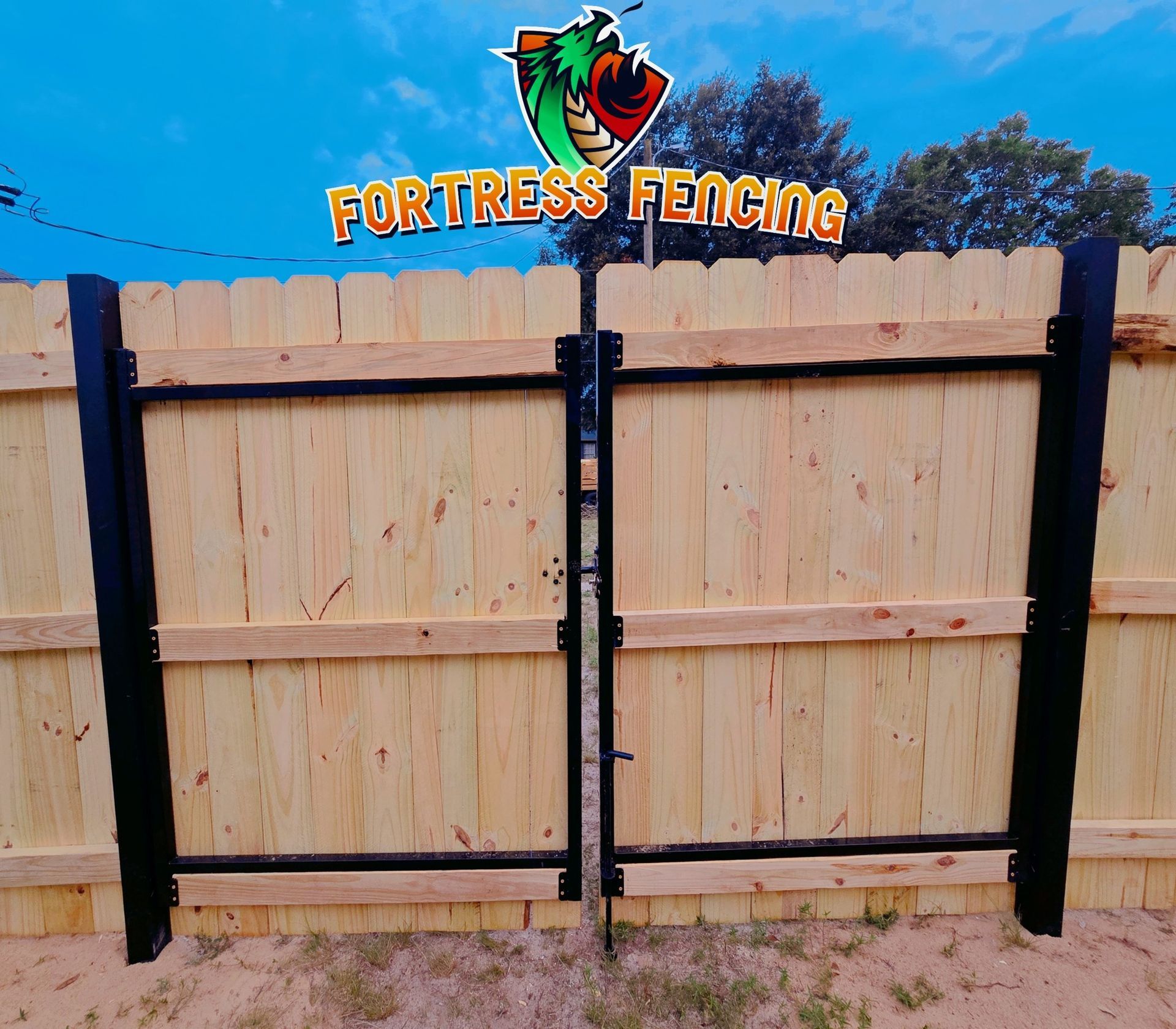 Wooden fence with black gate and company sign;