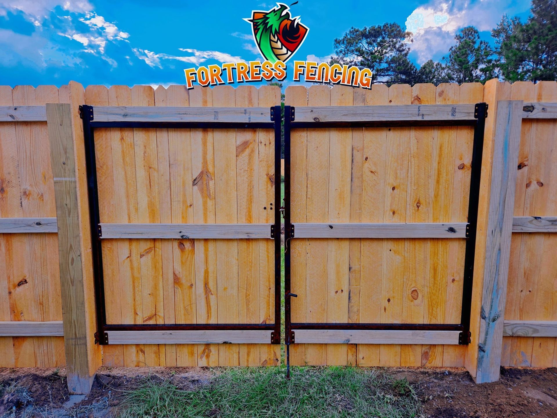 Wooden double gate in a wooden fence with Fortress Fencing logo.