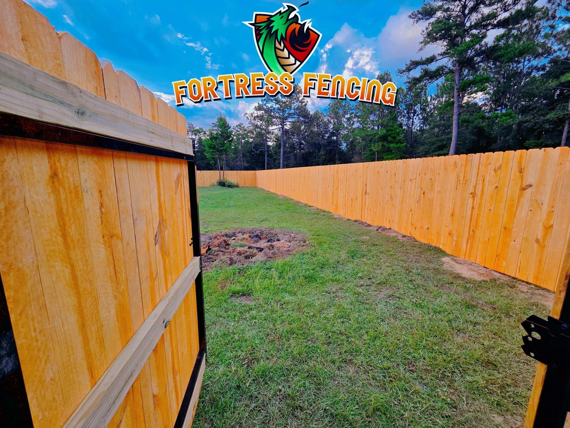 Wooden fence surrounds a grassy yard. Company logo