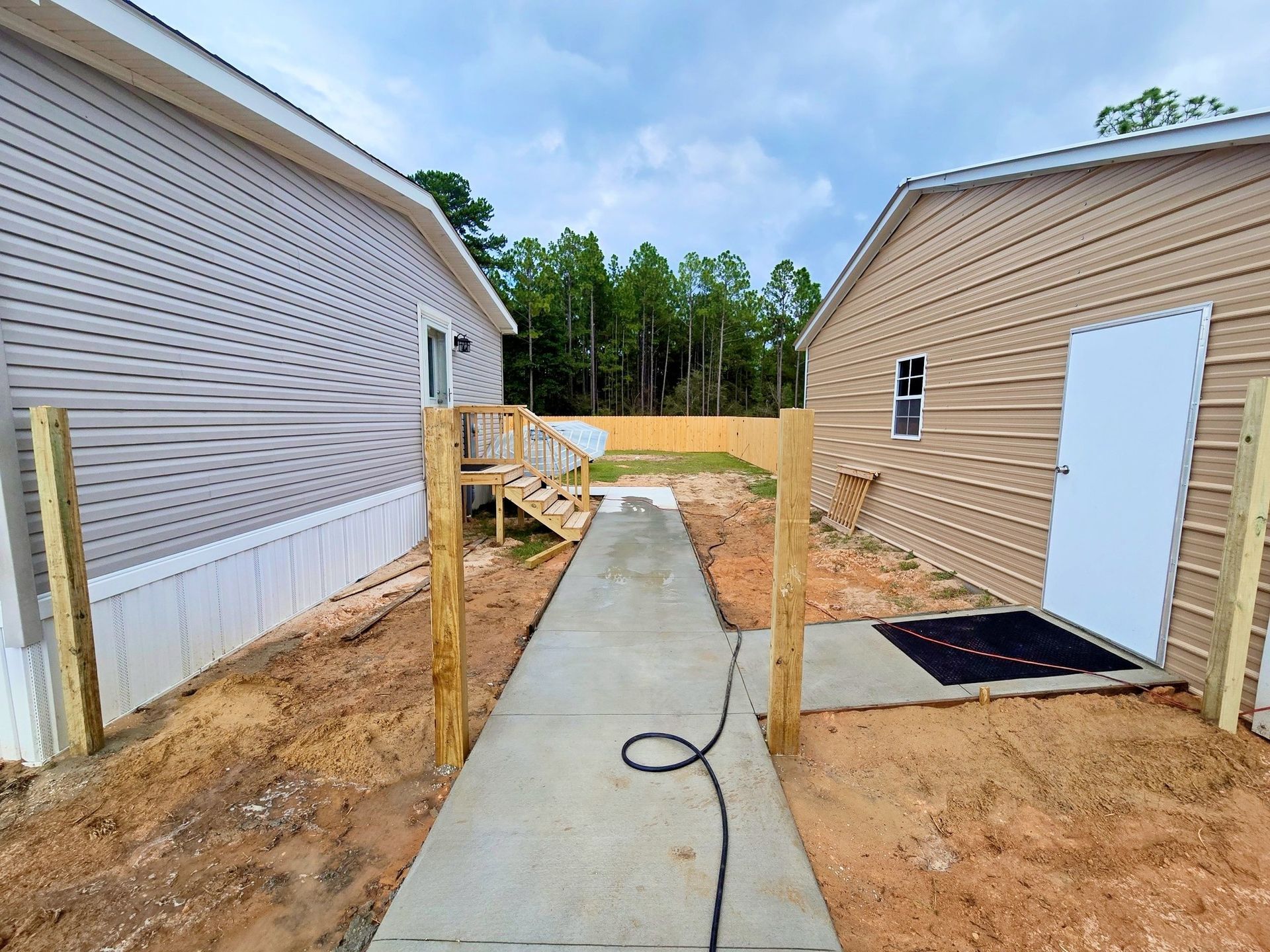 Concrete path between two buildings with wooden fence and ramp.