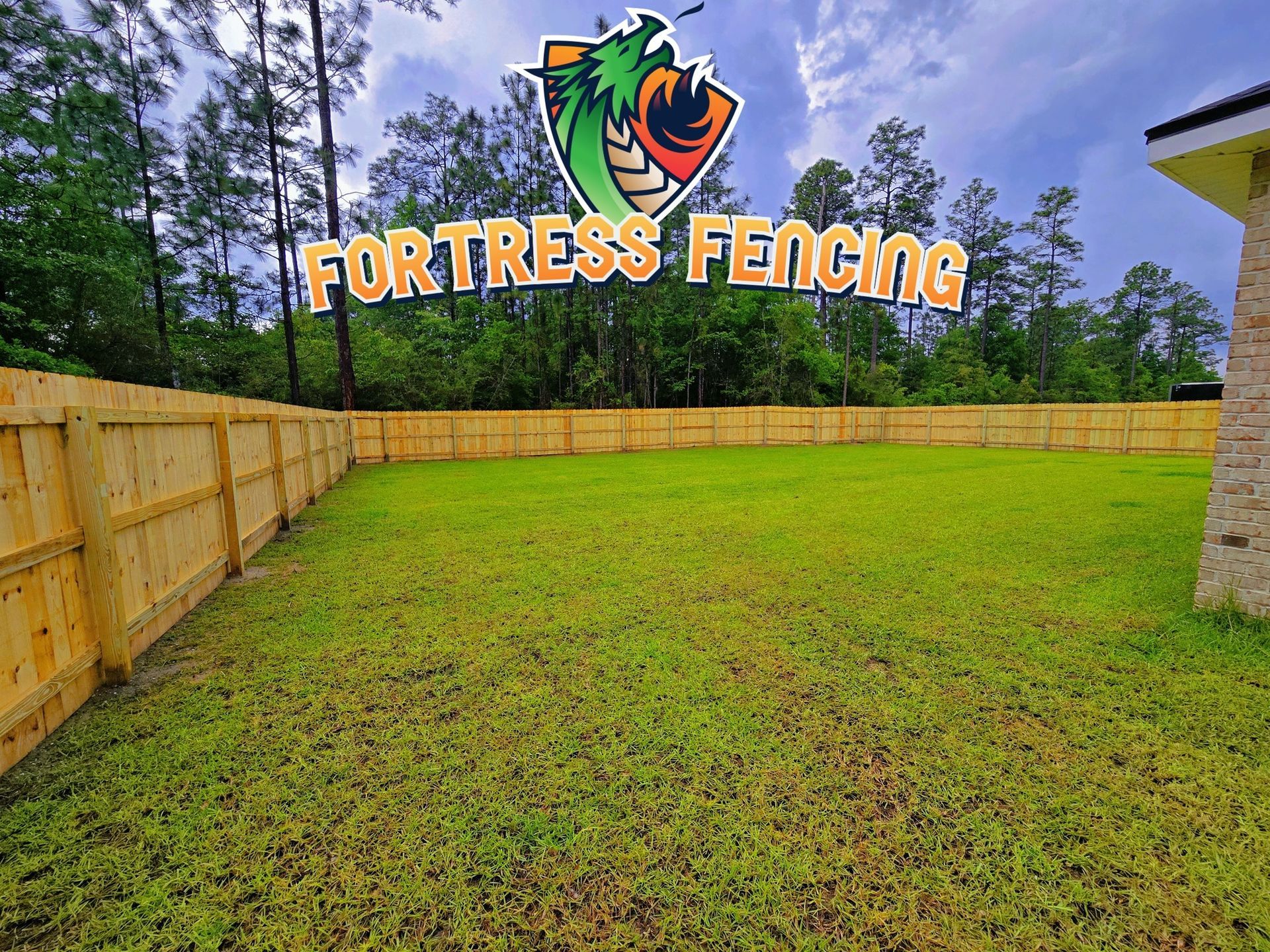 Wooden fence encloses a green yard with Fortress Fencing logo overlaid.