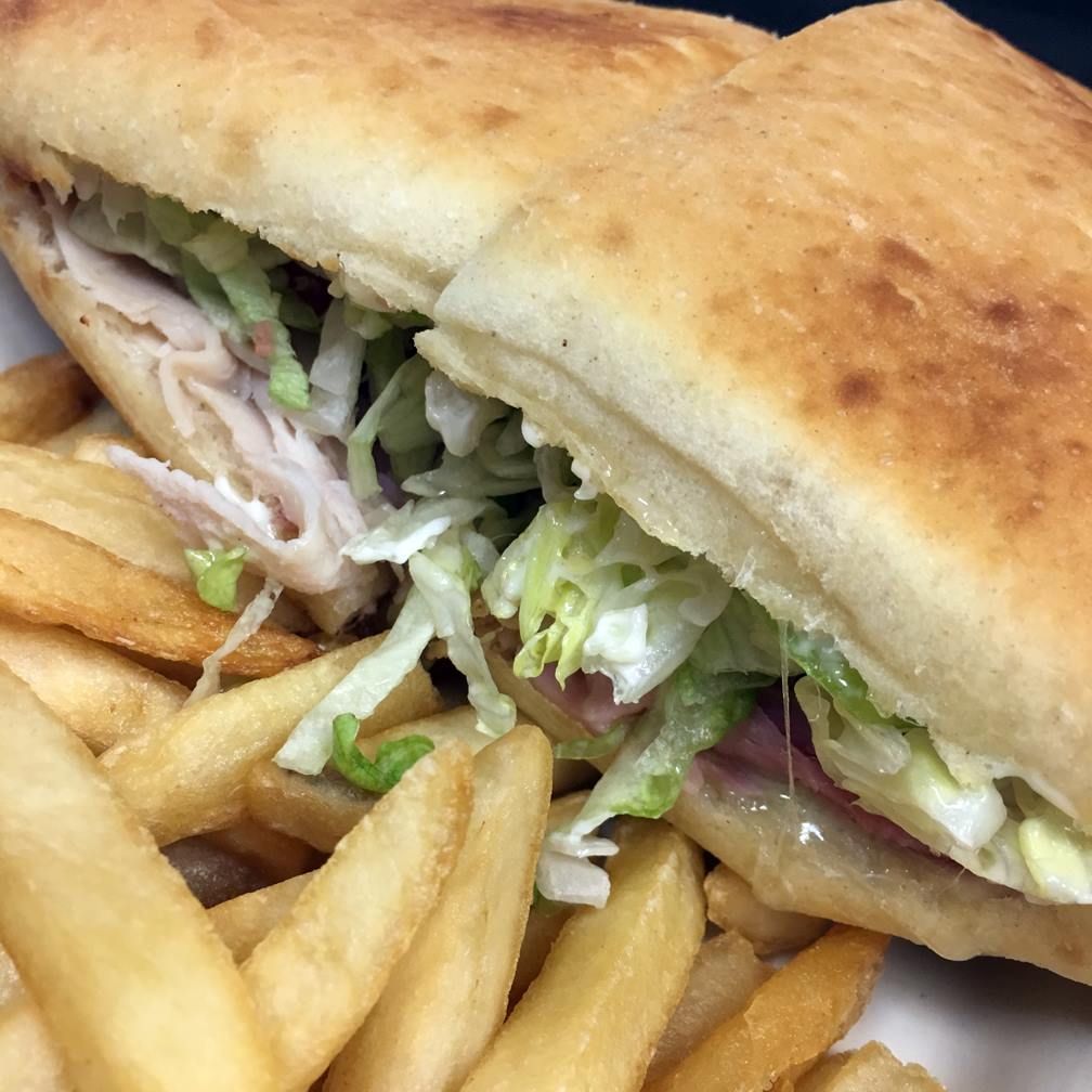 Turkey sandwich with lettuce and fries on a plate.