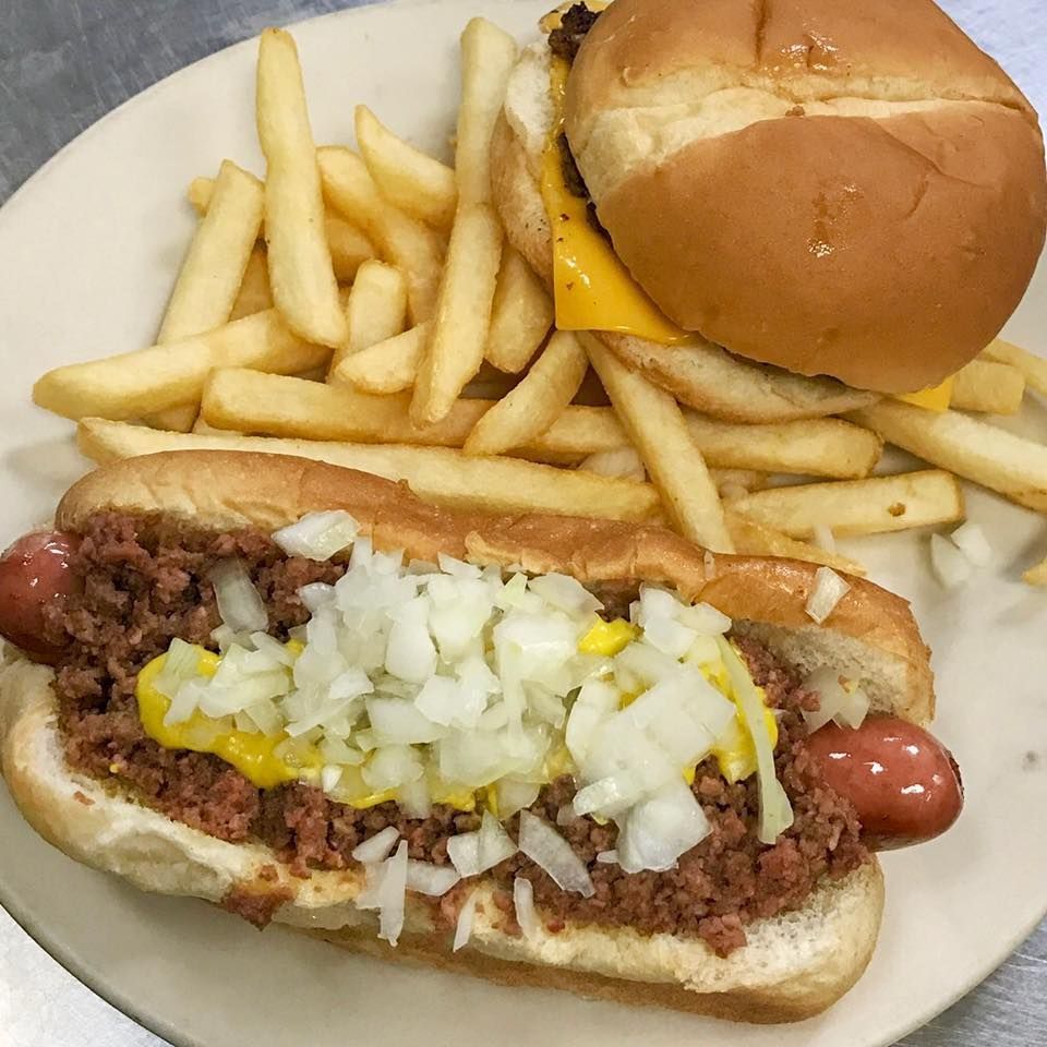 Hotdog with chili, onions, and mustard, cheeseburger, and fries on a plate.