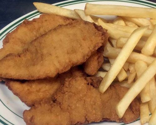 Fried chicken tenders and french fries on a white plate with green trim.